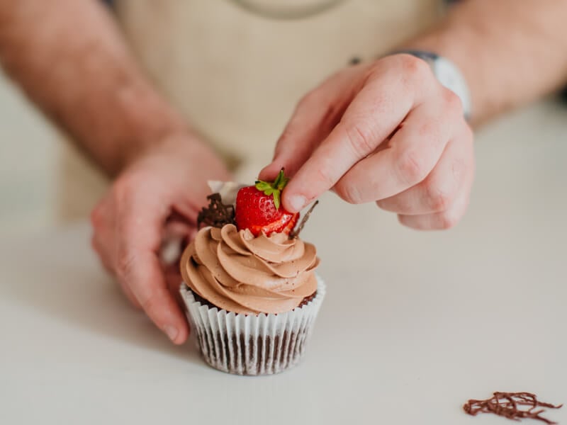 close-up of an iced chocolate cupcake with a strawberry on top
